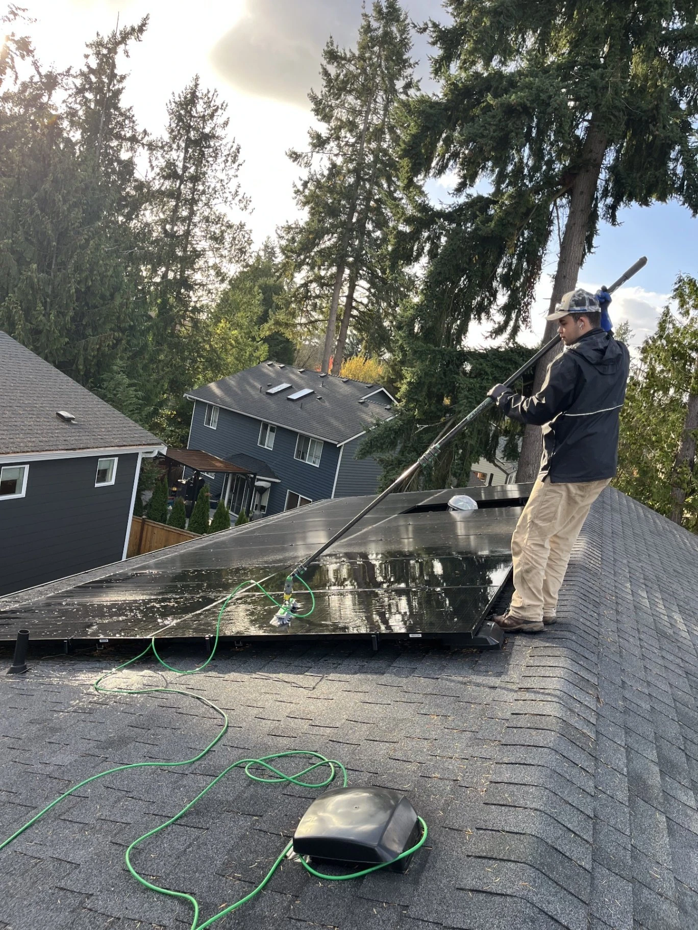 Same solar panels being brushed clean with a water-fed pole