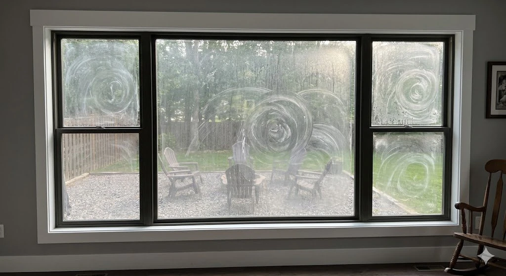 Large picture window covered in smears, dust, and handprints before cleaning
